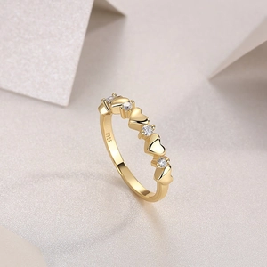 Macro detail of gold S925 silver ring featuring heart shapes and moissanite stones