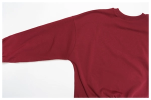 Detail of ribbed crewneck and drop shoulder seams on burgundy long-sleeve sweatshirt