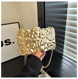 Close-up of golden metallic clutch with wavy texture and fine chain strap detail