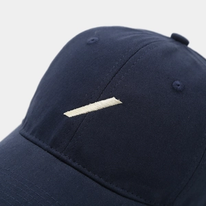 Detailed macro view of navy blue cotton baseball cap with white slash embroidery
