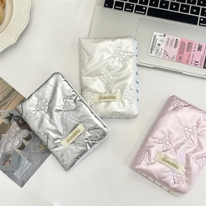 Detailed view of quilted bow-patterned PU passport holders in silver, white, and pink