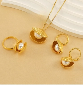 Detail of gold stainless steel jewelry set featuring shell designs and white pearls