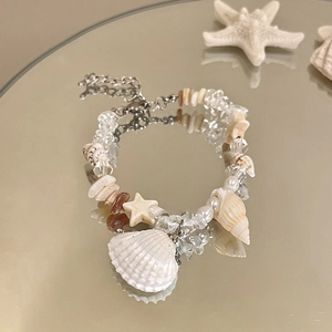 Detail of seashell bracelet with pearls and starfish on a reflective surface
