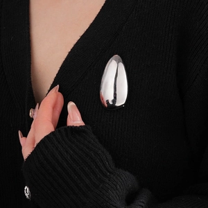 Polished silver irregular oval brooch on black cardigan for minimalist fashion style