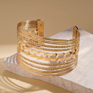 Detailed macro of gold layered metal cuff bracelet with wide geometric openwork