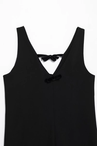 Détail d'une robe noire sans manches en tricot avec des nœuds décoratifs en velours