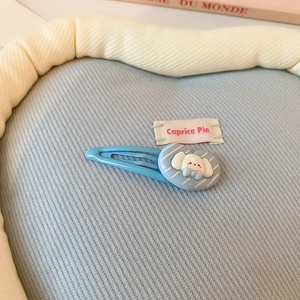 Détail d'une pince à cheveux Cinnamoroll bleue avec cœur rayé sur fond en tissu doux
