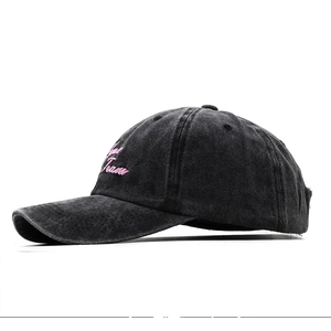 Detail of pink Love Team script embroidery on a washed vintage charcoal baseball cap