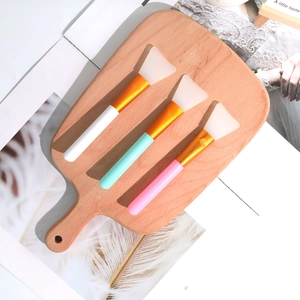 Dettaglio di tre pennelli in silicone per maschera viso con manici color pastello