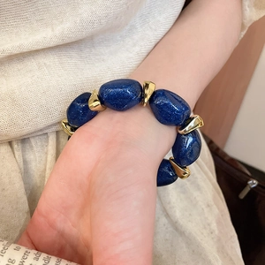 Detailed close-up of oval acrylic beads with gold metallic accents on a wrist