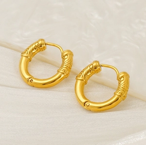 Detail shot of golden hoop earrings featuring vintage engraved cloud patterns on silk fabric