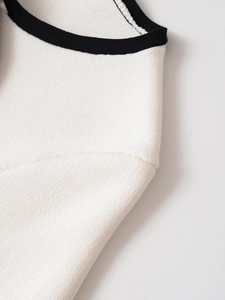 Detail of white knit top showing contrast black ribbed neckline and high-quality texture