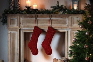 Close-up of red cable knit Christmas stockings hanging on a wooden fireplace mantle