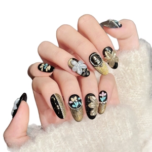 Faux ongles luxe noir et or avec fleurs 3D, strass et perles pour manucure chic