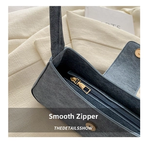 Detail view of grey-blue suede bag interior featuring golden zipper and magnetic closure