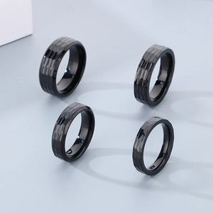 Detail of faceted black stainless steel rings in varied widths with hammered texture