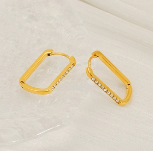 Close-up of gold U-shaped earrings with side-set cubic zirconia on white fabric