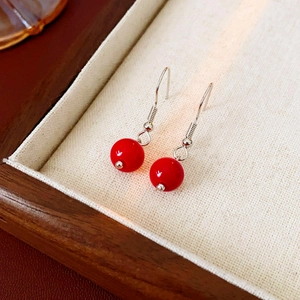 Détail de boucles d'oreilles ethniques en perles rouges avec crochets en argent sur plateau