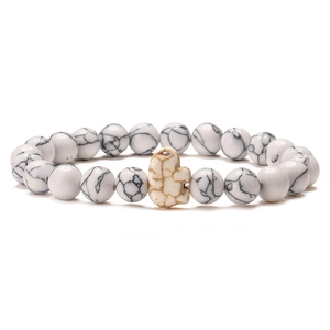 Macro detail of white marble turquoise beaded bracelet with elephant charm on plain background