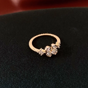Gros plan d'une bague trèfle en or rose avec zircons sertis et bordure de perles fines