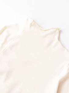 Detail of cream white knit top featuring a mock neck collar and raglan sleeve texture