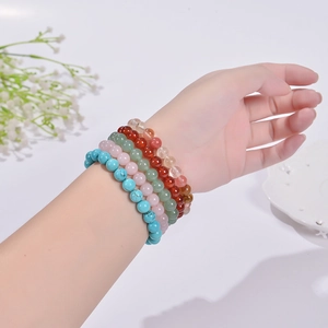 Close-up of five colorful 8mm natural stone beaded bracelets worn on a wrist