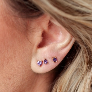 Close-up of heart and teardrop shaped purple zircon stud earrings worn by a model