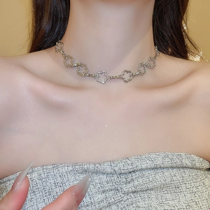 Close-up of silver necklace with hollow clover flower charms on elegant model neck