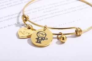 Close-up of golden adjustable wire bracelet with heart Love charm and round kid icon