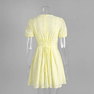 Detail of yellow cotton dress with eyelet embroidery and cross-back lace-up design