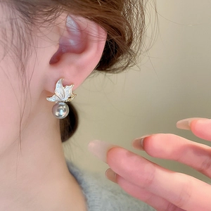 Close-up of butterfly pearl drop earring with silver-grey pearl on female ear