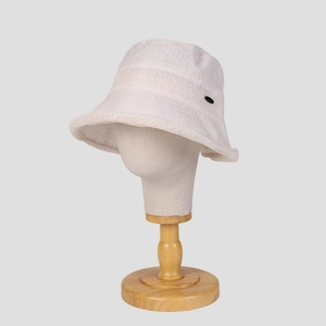 Detail of white woven bucket hat texture and black oval metal logo on a mannequin
