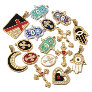Detail of gold and silver charms featuring enamel evil eye and cross pendants