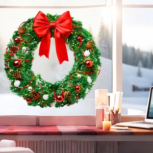 Christmas wreath with red bow and pine cones hanging on a snowy window in a cozy room
