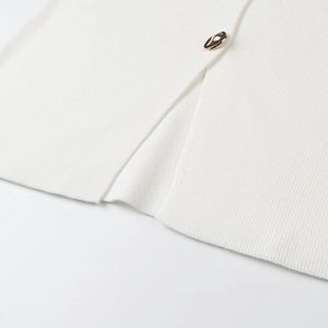 Detail of white ribbed knit fabric with side slit and decorative gold button