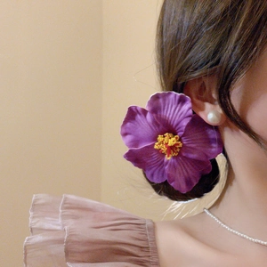 Detail of purple hibiscus flower hair clip with yellow pistil on woman's side bun