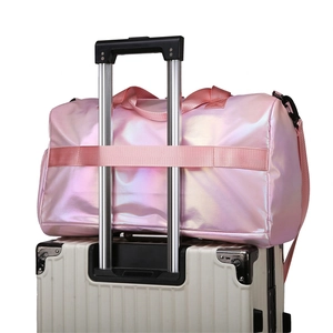Pink iridescent fitness bag showing trolley sleeve functionality on white suitcase