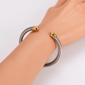 Two-tone stainless steel cable wire cuff bracelet with golden ball ends on hand model