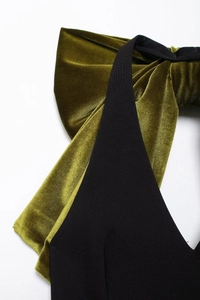 Gros plan du nœud en velours sur le cou licou avec décolleté en V de la robe noire