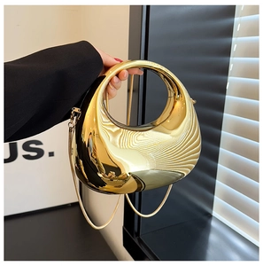 Macro view of metallic gold mirror finish handbag with elegant circular hollow handle