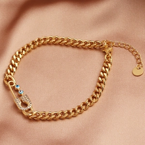 Pulsera de cadena cubana dorada con dije de imperdible y ojo turco sobre seda fina