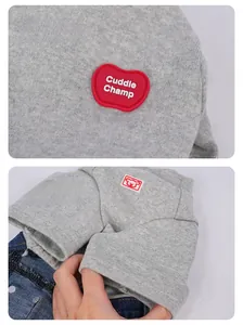 Detail van grijze gebreide kleding voor huisdieren met rode appelpatch en logo
