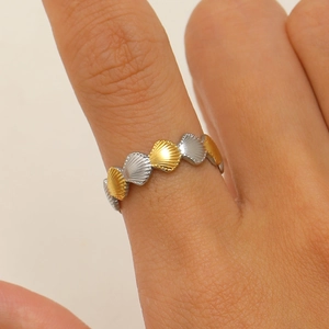 Dettaglio ravvicinato di un anello a conchiglia bicolore oro e argento sulle dita