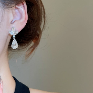 Detailed close-up of silver water drop earrings with sparkling leaf design and crystals