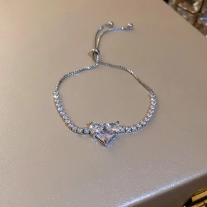 Macro shot of silver zircon heart bracelet with adjustable slider on beige leather background