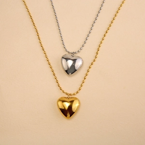 Detail of gold and silver heart pendants on bead chains with metallic luster finish