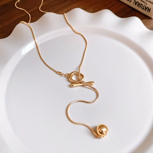 Detail view of a gold snake chain necklace with an OT toggle clasp and spherical pendant
