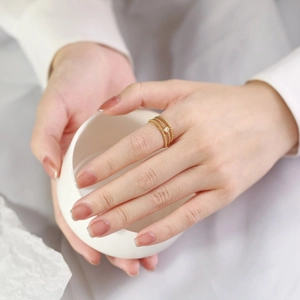 Detailansicht eines vergoldeten gedrehten Rings mit einem kleinen funkelnden Zirkonstein