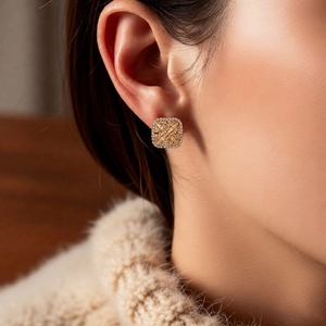 Macro shot of gold square geometric earrings with pavé zircons worn on ear