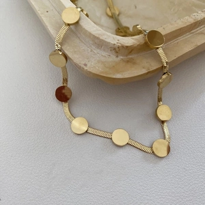 Détail du collier en acier titane doré avec pendentifs circulaires plats et chaîne